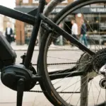 A close-up of an electric bike's battery pack alongside a mechanical bike's classic derailleur